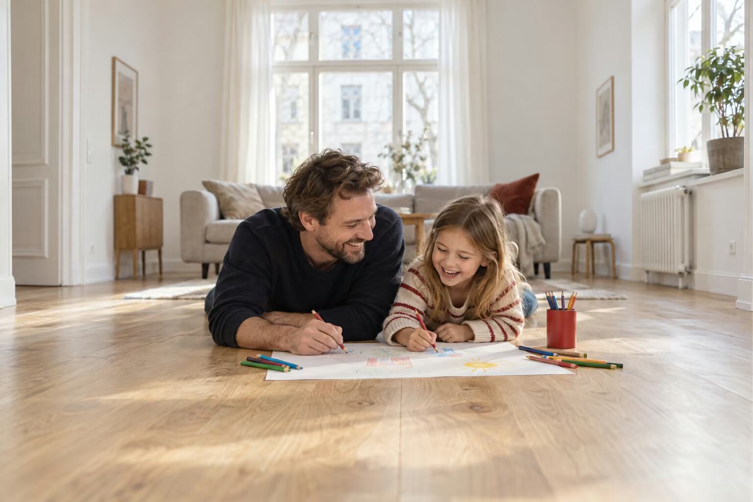Vater und Tochter malen auf dem neuen Holzboden im Wohnzimmer