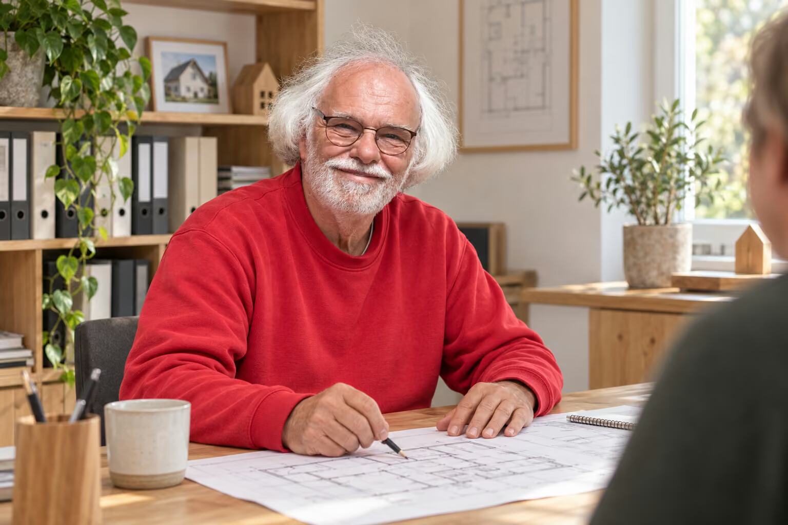 Joachim Woermann bespricht am Schreibtisch einen Hausplan mit einem Kunden